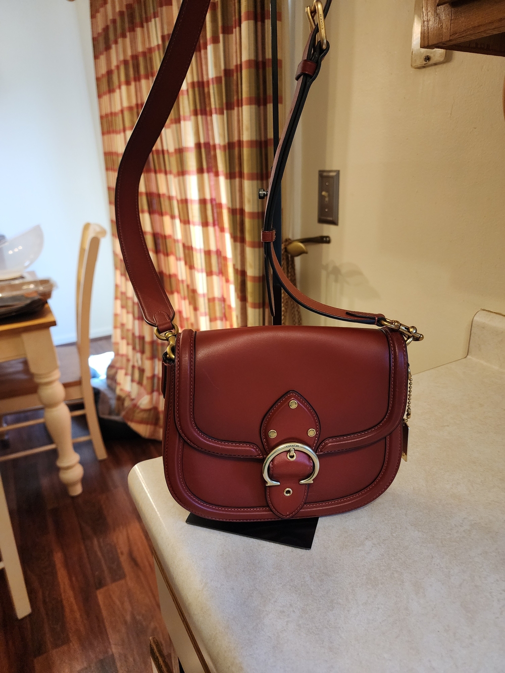 Coach Beat Saddle Bag in a rich red leather features the brand's signature brass